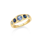 A gold ring featuring a curved band with five round blue gemstones, including one larger light blue center stone and two smaller dark blue stones on each side.