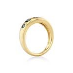 A polished yellow gold ring featuring three small dark blue gemstones set along the upper outer edge.