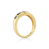 A polished yellow gold ring featuring three small dark blue gemstones set along the upper outer edge.