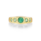 A yellow gold ring featuring five green gemstones set in a curved row.