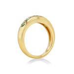 A polished yellow gold ring featuring three small green gemstones set along the upper curve.