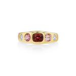 A yellow gold ring featuring a central cushion-cut deep red gemstone flanked by two oval pink gemstones and two small round clear stones, shown on a clean white background.