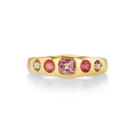 A gold ring featuring a central cushion-cut pink gemstone flanked by two round pink stones and two smaller oval clear stones.