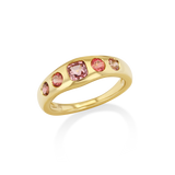 A gold band ring featuring five pink gemstones of varying sizes.