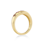 A polished yellow gold ring with a row of small pink gemstones set along the top.