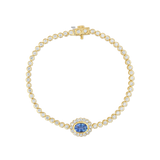 A yellow gold tennis bracelet featuring round-cut clear stones and a central oval blue sapphire surrounded by a halo of small clear stones, displayed on a clean white background.