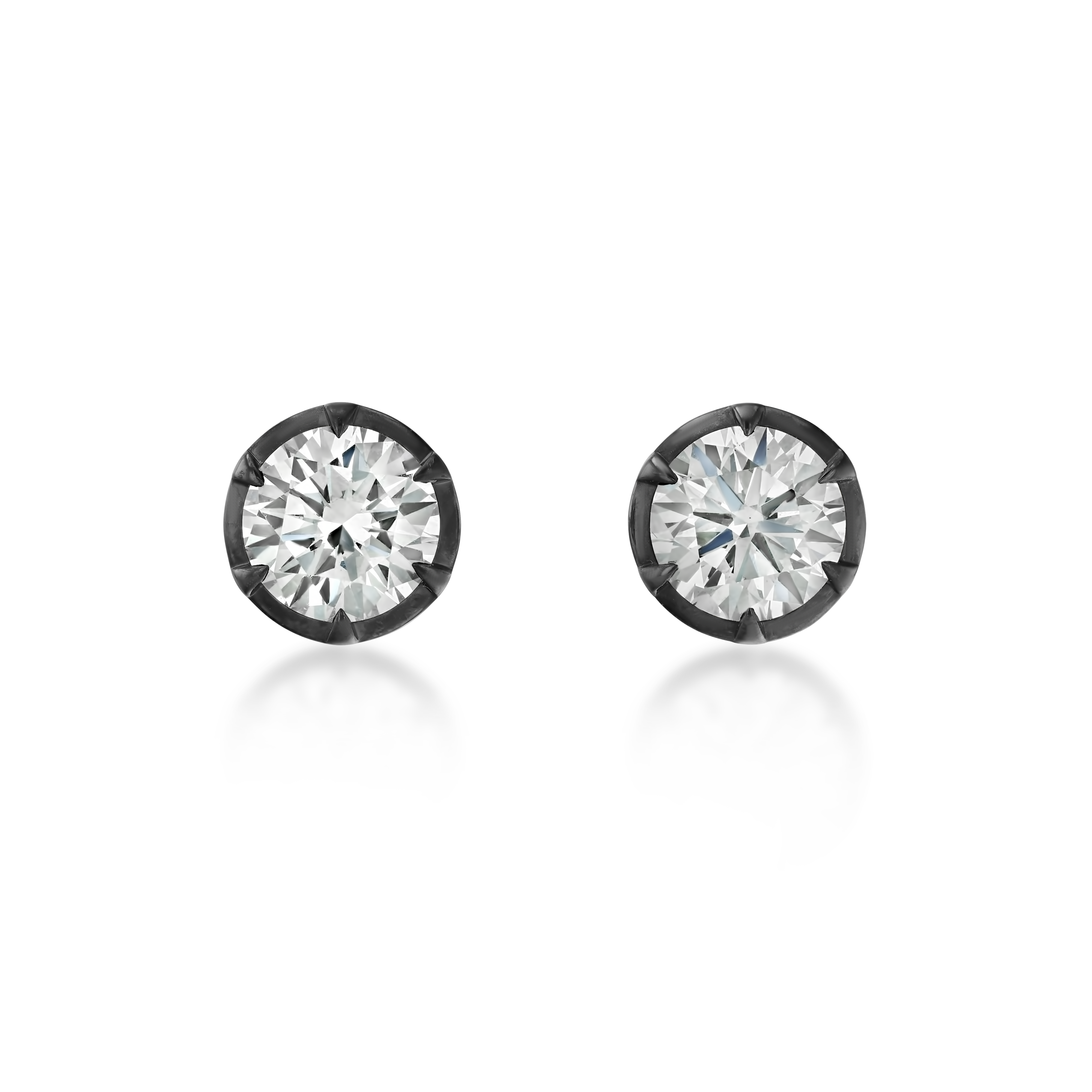 A pair of round-cut stud earrings with brilliant clear gemstones in dark metal bezel settings, shown on a clean white background with soft reflections below.