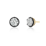 A pair of round-cut stud earrings with clear gemstones in black bezel settings and yellow gold posts, shown on a clean white background.