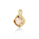 A gold pendant featuring a large, rough-cut peach-colored gemstone, shown on a clean white background with a soft reflection below.