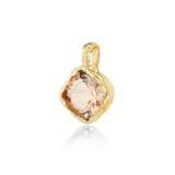 A gold pendant featuring a large, rough-cut peach-colored gemstone, shown on a clean white background with a soft reflection below.