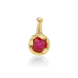 A gold pendant featuring a round faceted pinkish-red gemstone in a textured bezel setting, shown on a clean white background with a soft reflection below.