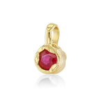 A gold pendant featuring a faceted round red gemstone in a textured, organic-shaped bezel setting, shown on a clean white background with a soft reflection.