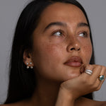 Woman with long dark hair and minimal makeup against a gray background