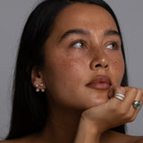 Woman with long dark hair and minimal makeup against a gray background