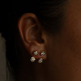 Close-up of an ear wearing three diamond stud earrings.