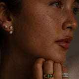 Close-up of a person wearing earrings and rings with a neutral background