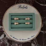 Two diamond rings in a green box on a decorative plate with 'Ralph's' branding.