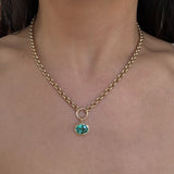 Gold chain necklace with a green gemstone pendant on a person's neck.