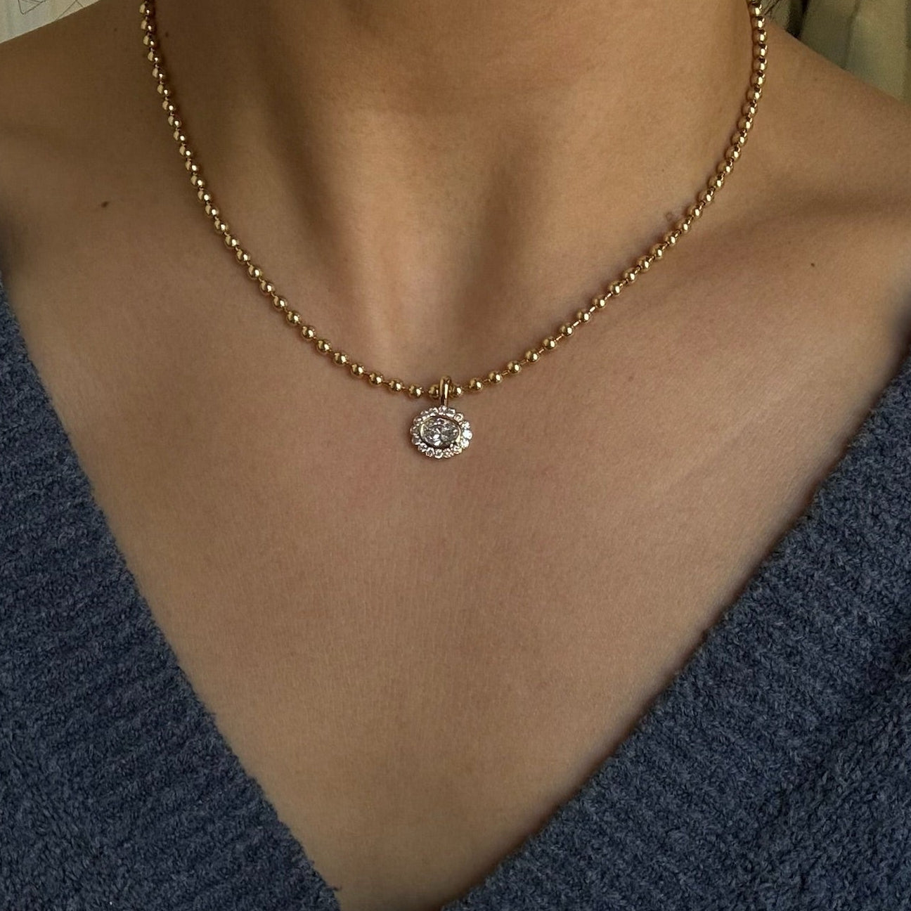 Necklace with a pendant worn by a person in a blue garment.