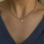 Necklace with a pendant worn by a person in a blue garment.