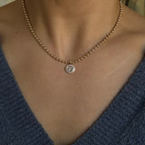 Necklace with a pendant worn by a person in a blue garment.