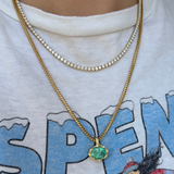Gold necklace with a green pendant on a white shirt with blue text