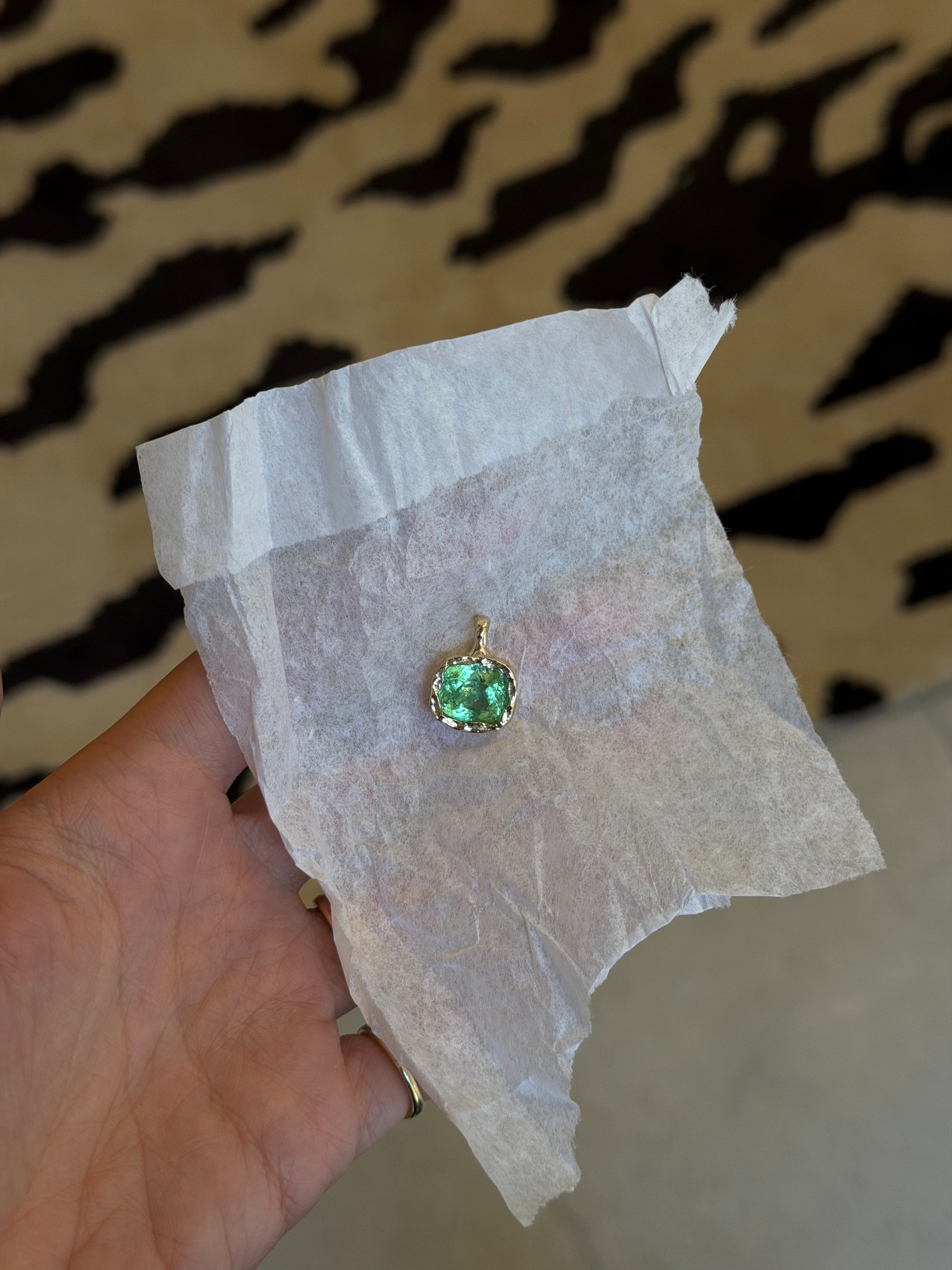 Paraiba electric green stone hammered in yellow gold in jewelers white paper